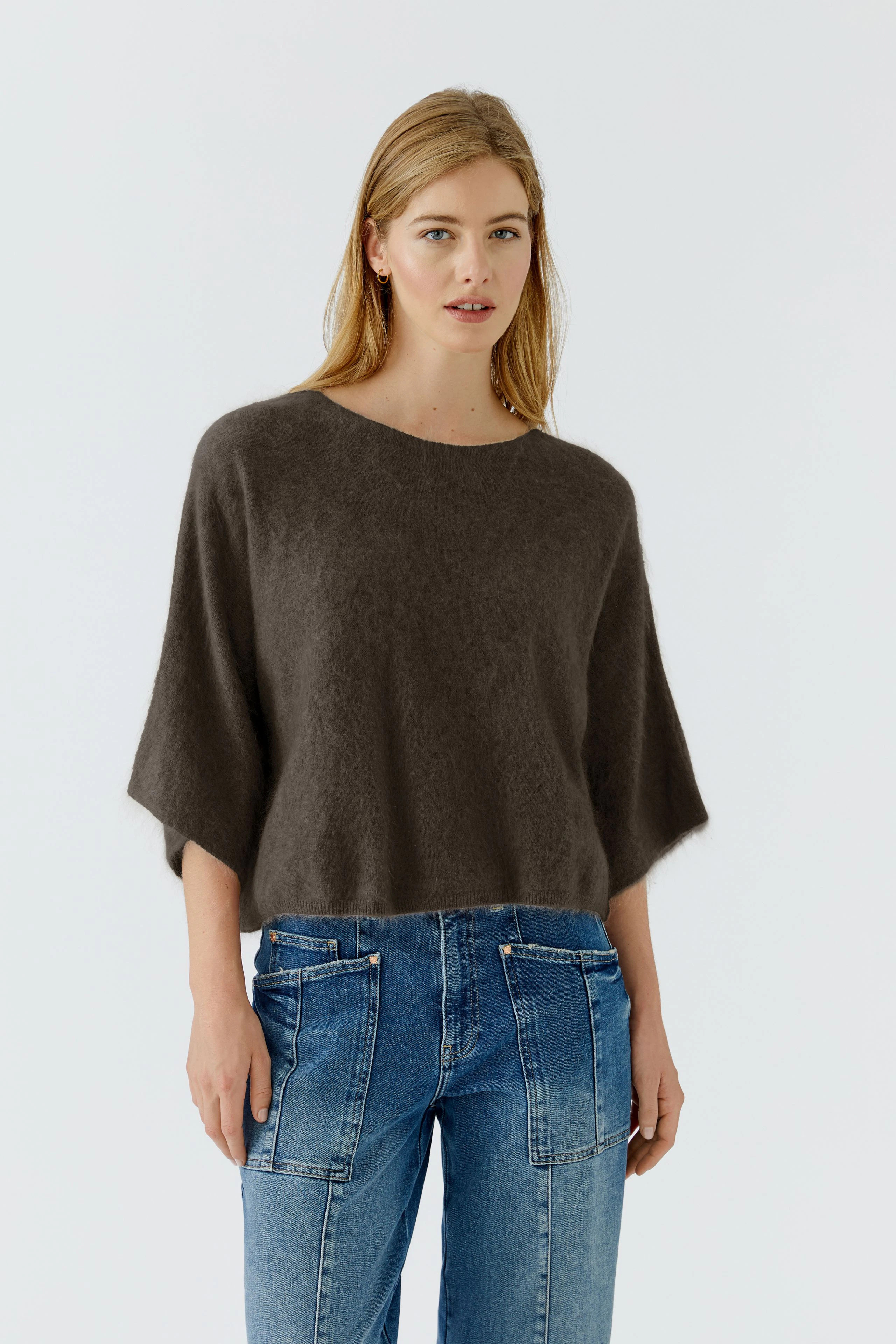 Lässiger Damen-Pullover: Frau im weiten, braunen Pullover und blauen Jeans, entspannt und modern.