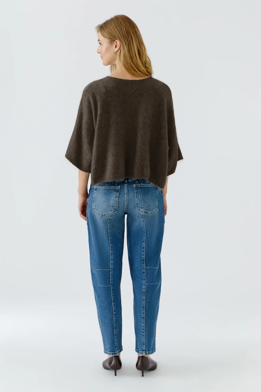 Casual pullover: Woman in a loose brown pullover and blue jeans, viewed from the back.