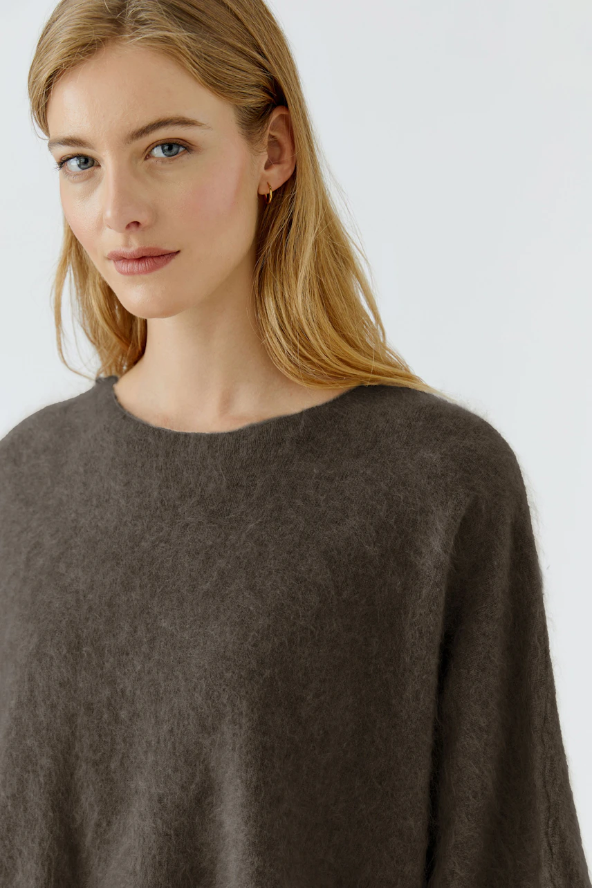 Casual women's pullover: Woman in a soft, brown pullover with a relaxed fit, looking serene.