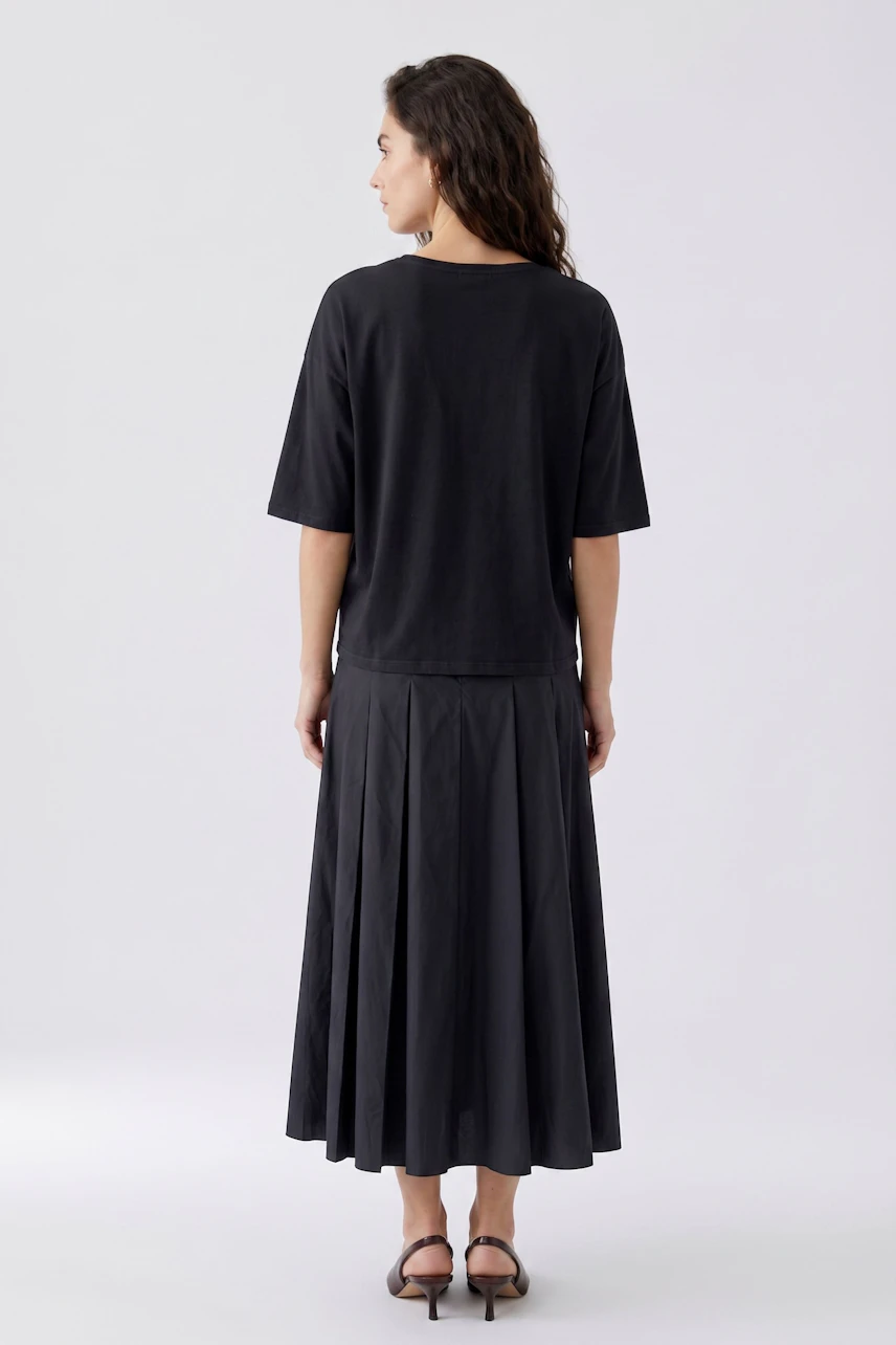 A-line skirt: Woman in a black A-line skirt and matching top, viewed from the back.