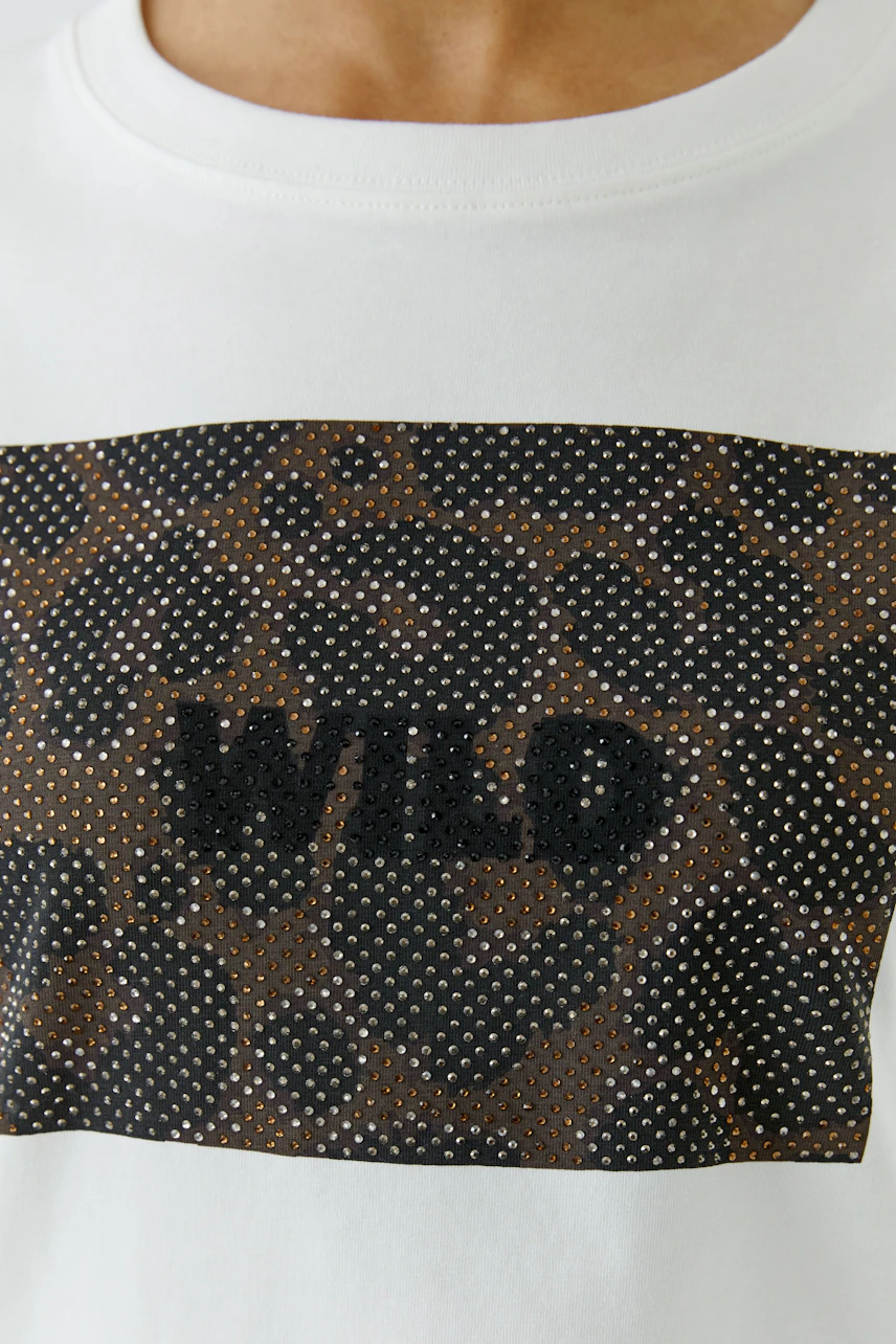 Weißes Damen-T-Shirt: Frau trägt T-Shirt mit "WILD"-Print und Leopardenmuster-Detail.