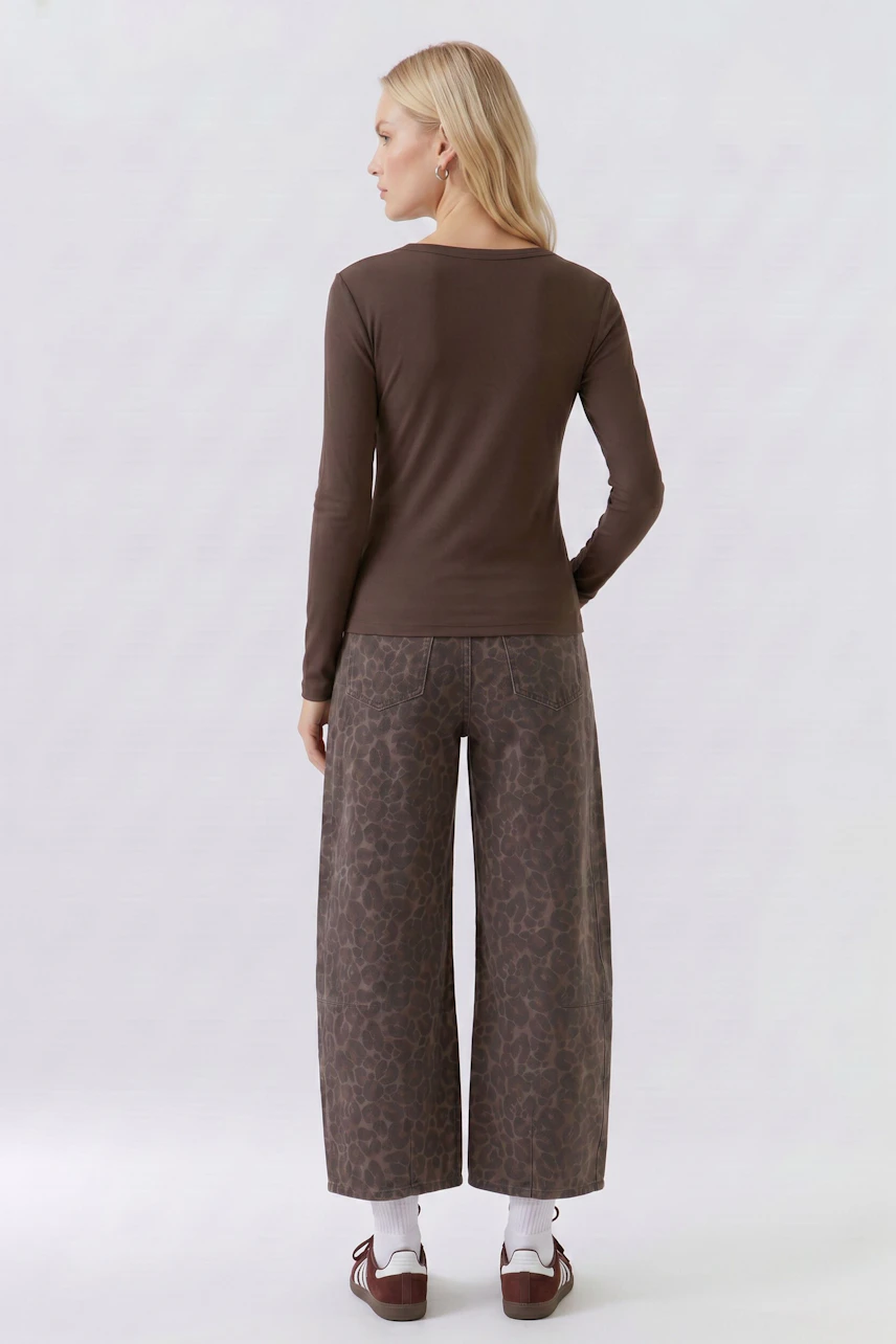 Woman in brown long-sleeve shirt and patterned pants, viewed from the back.
