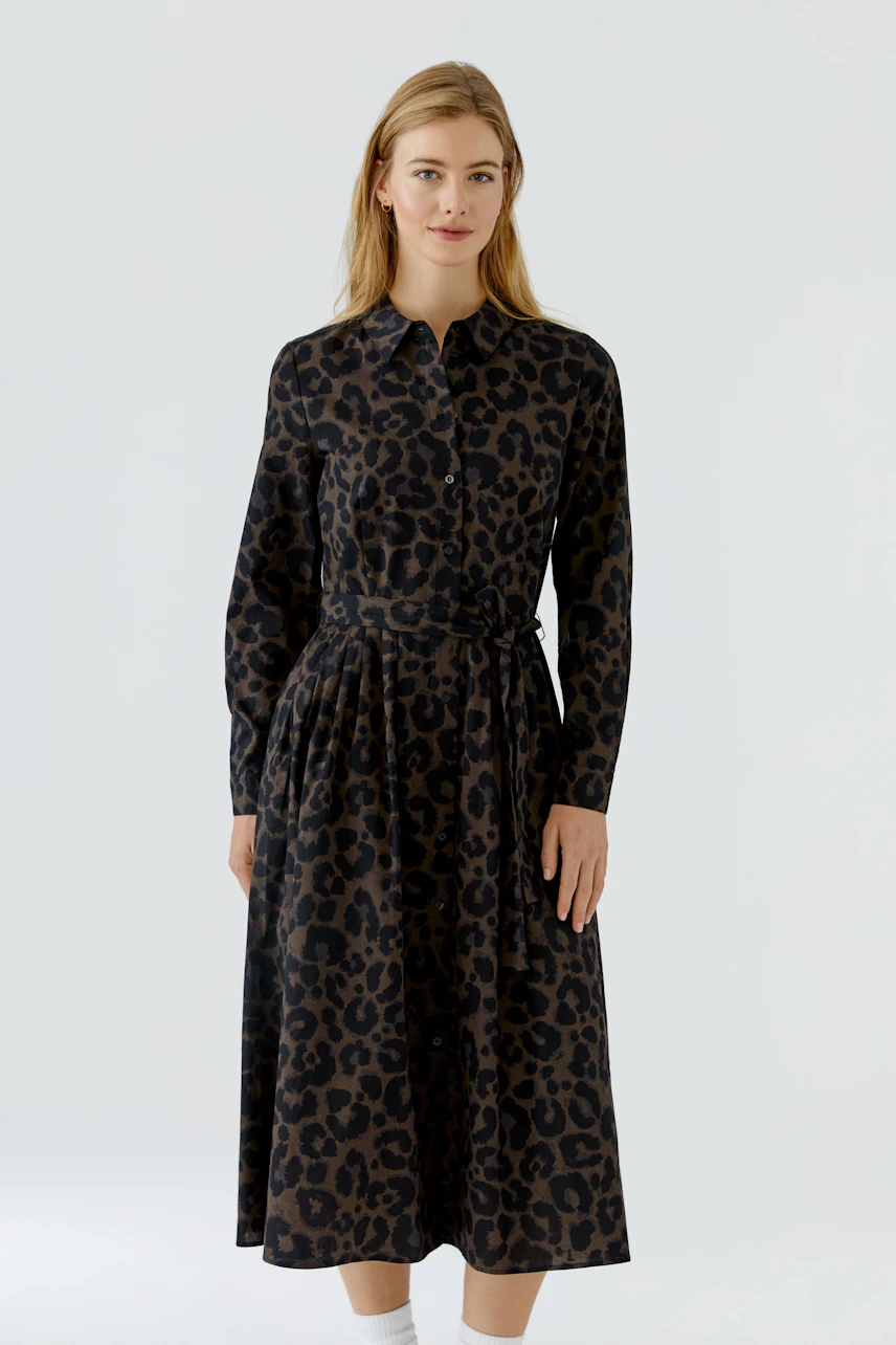 Leopard print midi dress: Woman in a stylish, belted dress with long sleeves, exuding confidence.
