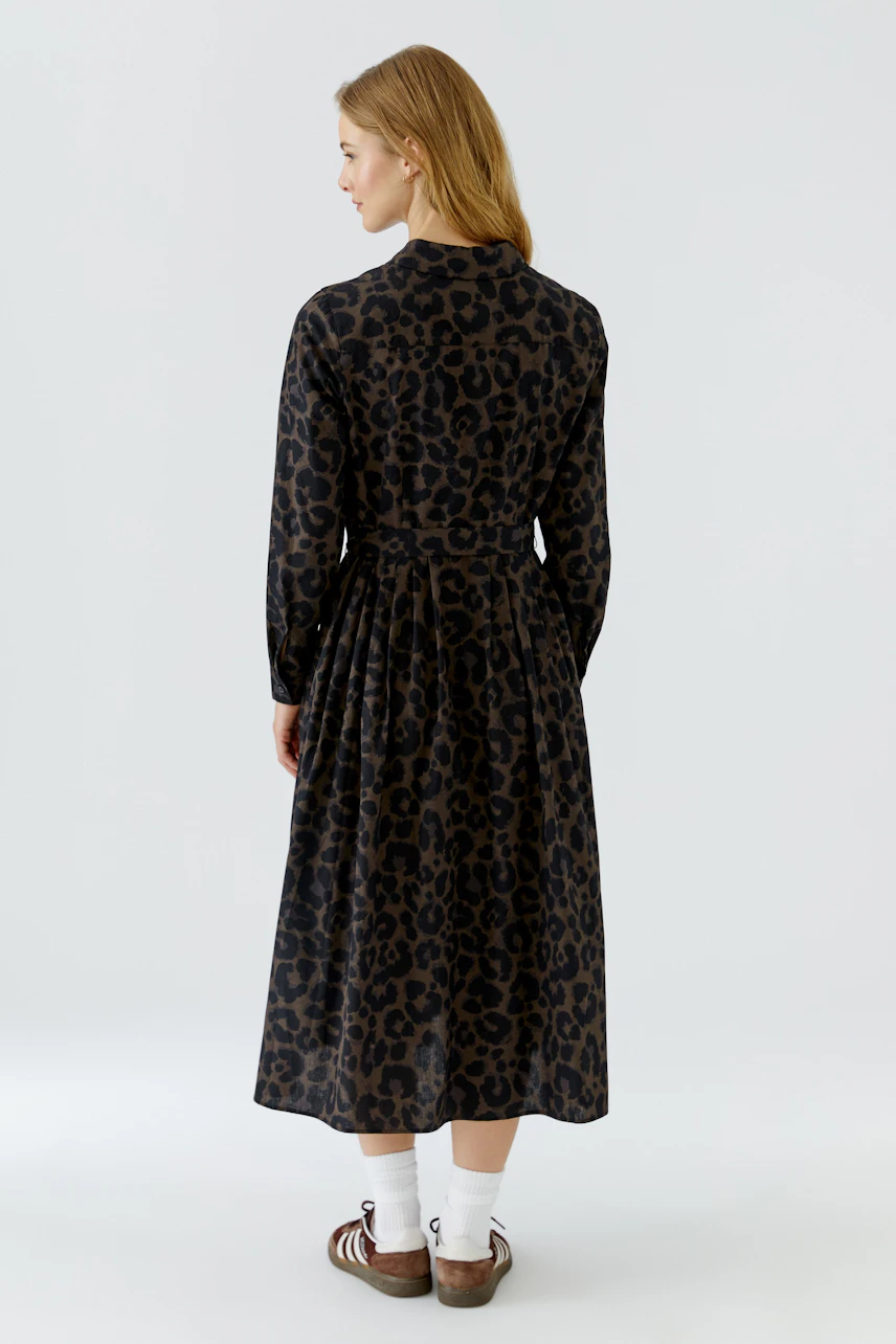 Casual midi dress: Woman in leopard print dress, white socks, and brown shoes, standing confidently.