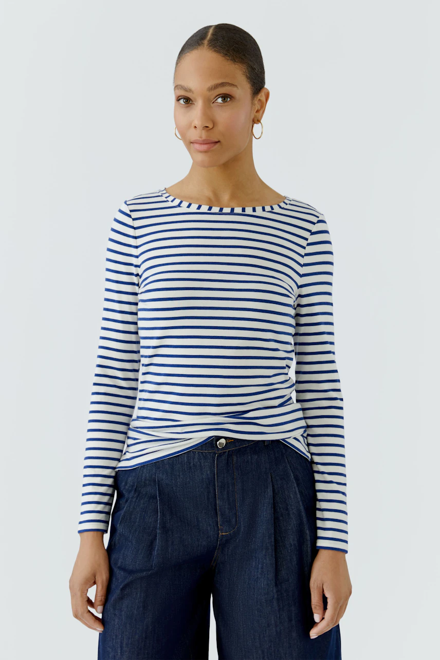 Gestreiftes Langarmshirt: Frau im blau-weiß gestreiften Shirt und dunkler Hose, lässig und modern.