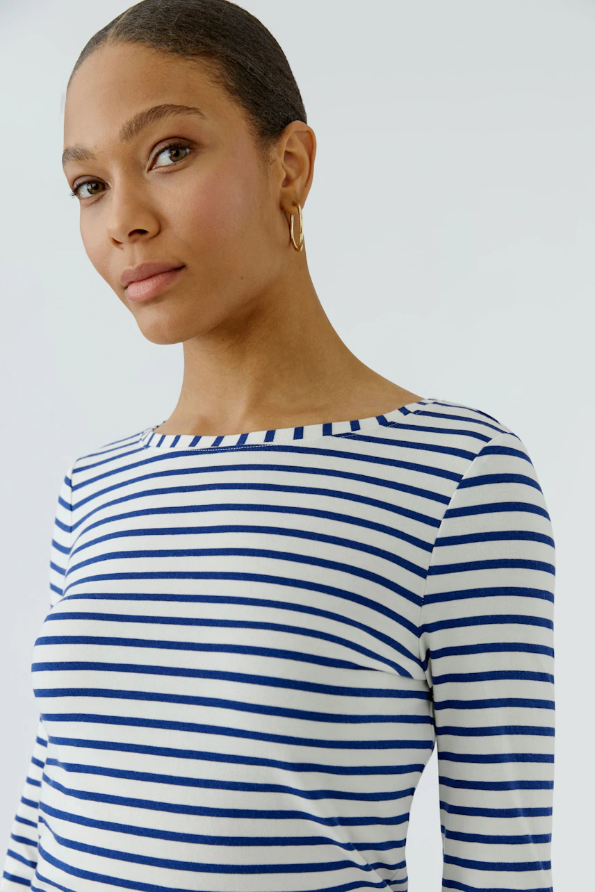 Damen-Langarmshirt: Frau im gestreiften Shirt mit blau-weißen Streifen und goldenen Ohrringen.
