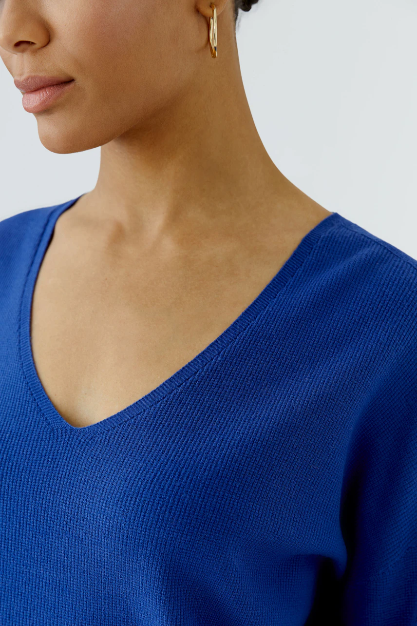 Casual women's pullover: Woman in a blue V-neck pullover, showcasing a simple and relaxed style.