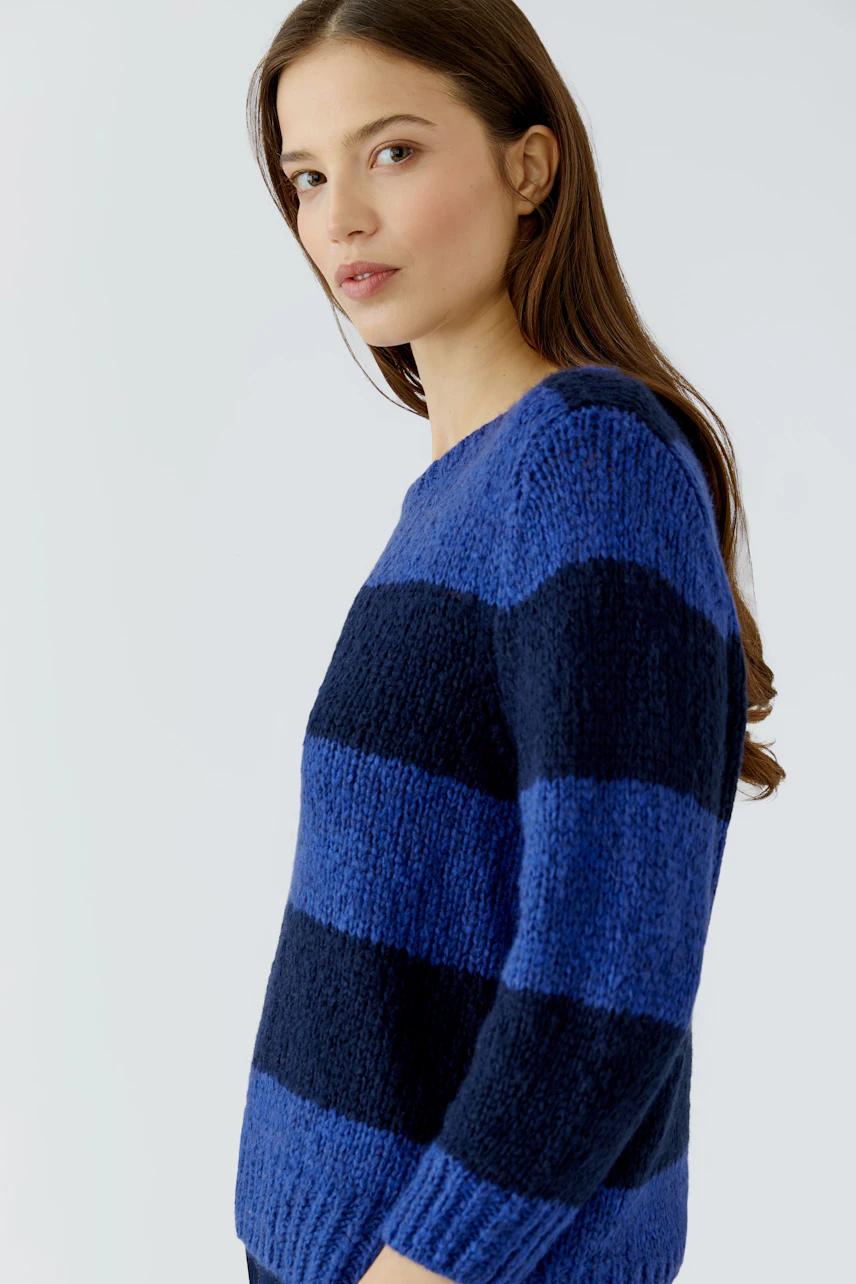 Casual women's pullover: Woman in a blue and navy striped pullover, looking confidently to the side.