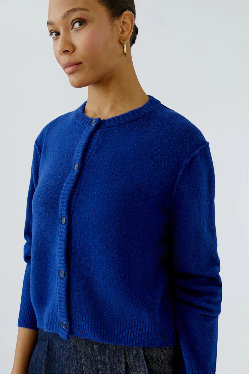 Casual women's cardigan: Woman in a blue knit cardigan with button-up front, paired with dark denim.