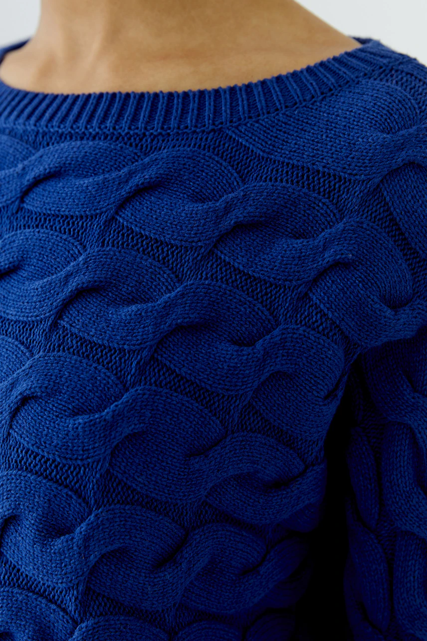 Blauer Damen-Pullover: Frau trägt strukturierten Pullover mit Wellenmuster, betont lässigen Stil.