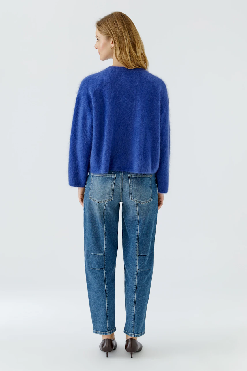 Frau im blauen Pullover und Jeans, Rückansicht. Lässiger Look für den Alltag.