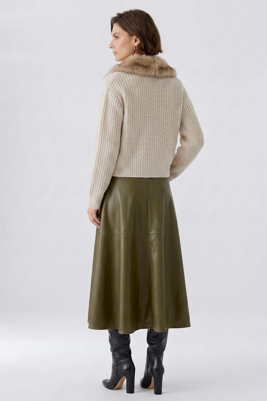 A-line skirt: Woman in olive leather skirt, beige sweater with fur collar, and black boots.