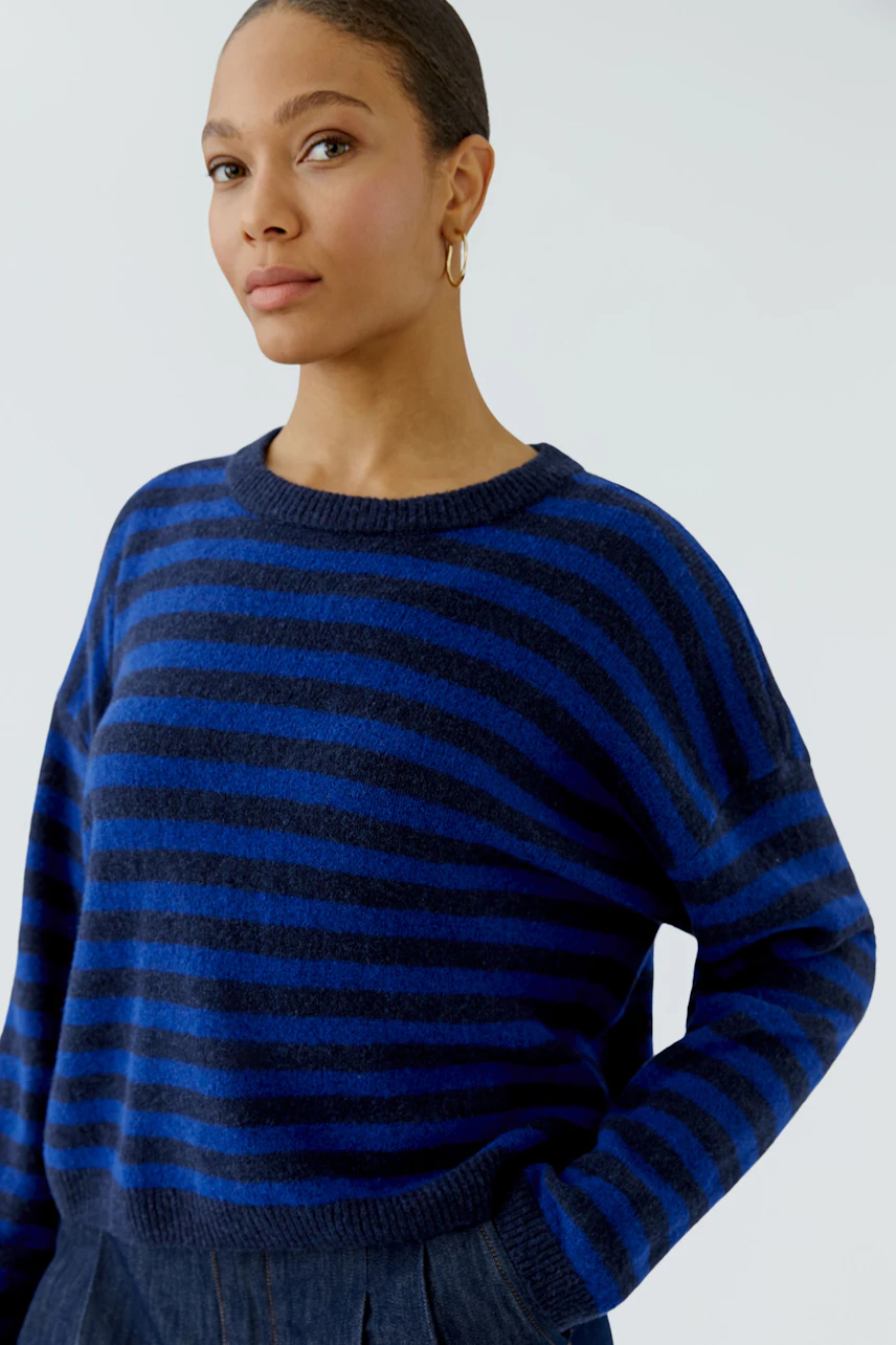 Casual women's pullover: Woman in blue striped pullover with a relaxed fit, looking confidently.