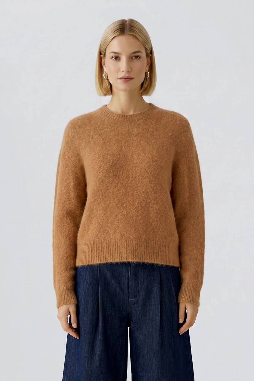 Damen-Pullover: Frau im braunen Pullover mit langen Ärmeln und blauer Hose, schlicht und modern.