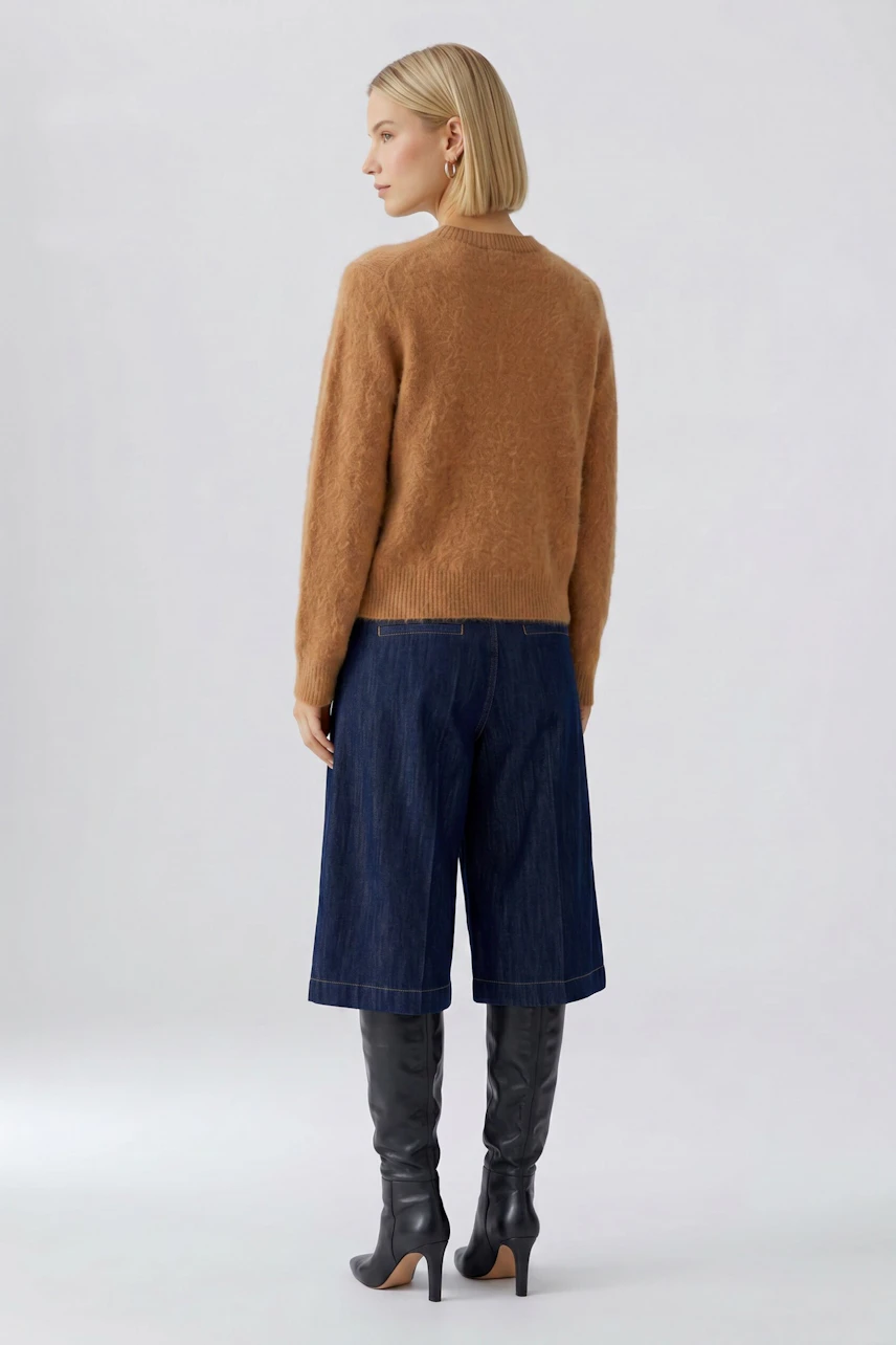 Damen-Pullover: Frau im braunen Pullover, kombiniert mit Jeans-Culottes und schwarzen Stiefeln, von hinten.