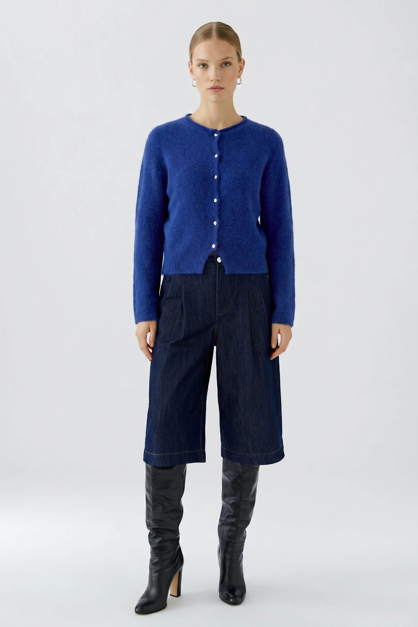 Woman in blue cardigan: Model wears a blue knit cardigan with pearl buttons, paired with denim culottes and black boots.