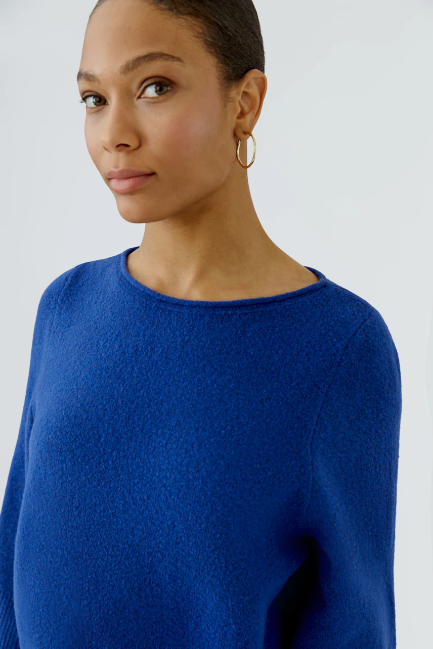 Woman in a vibrant blue pullover, simple design, looking confidently. Ideal for casual wear.