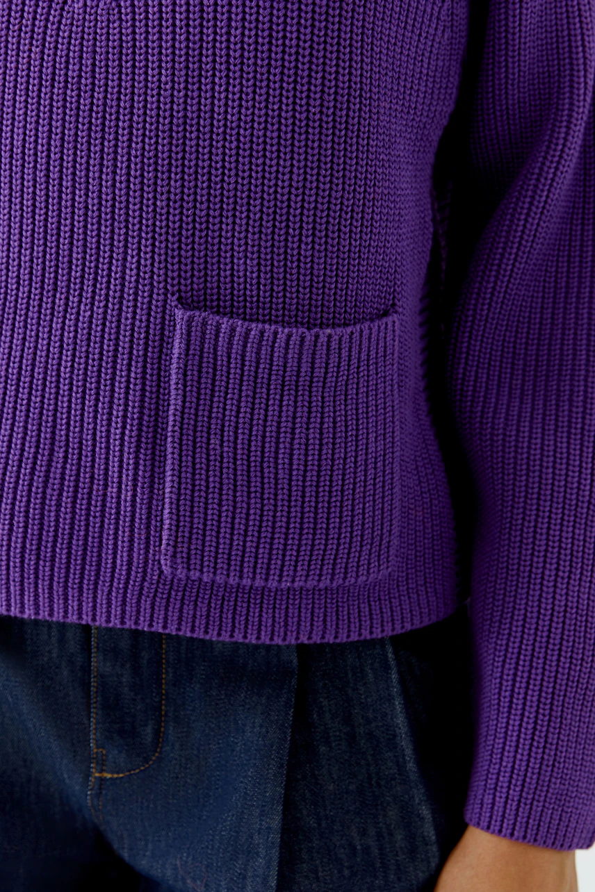 Lila Damen-Pullover: Grob gestrickter Pullover mit Tasche, kombiniert mit dunkler Jeans.