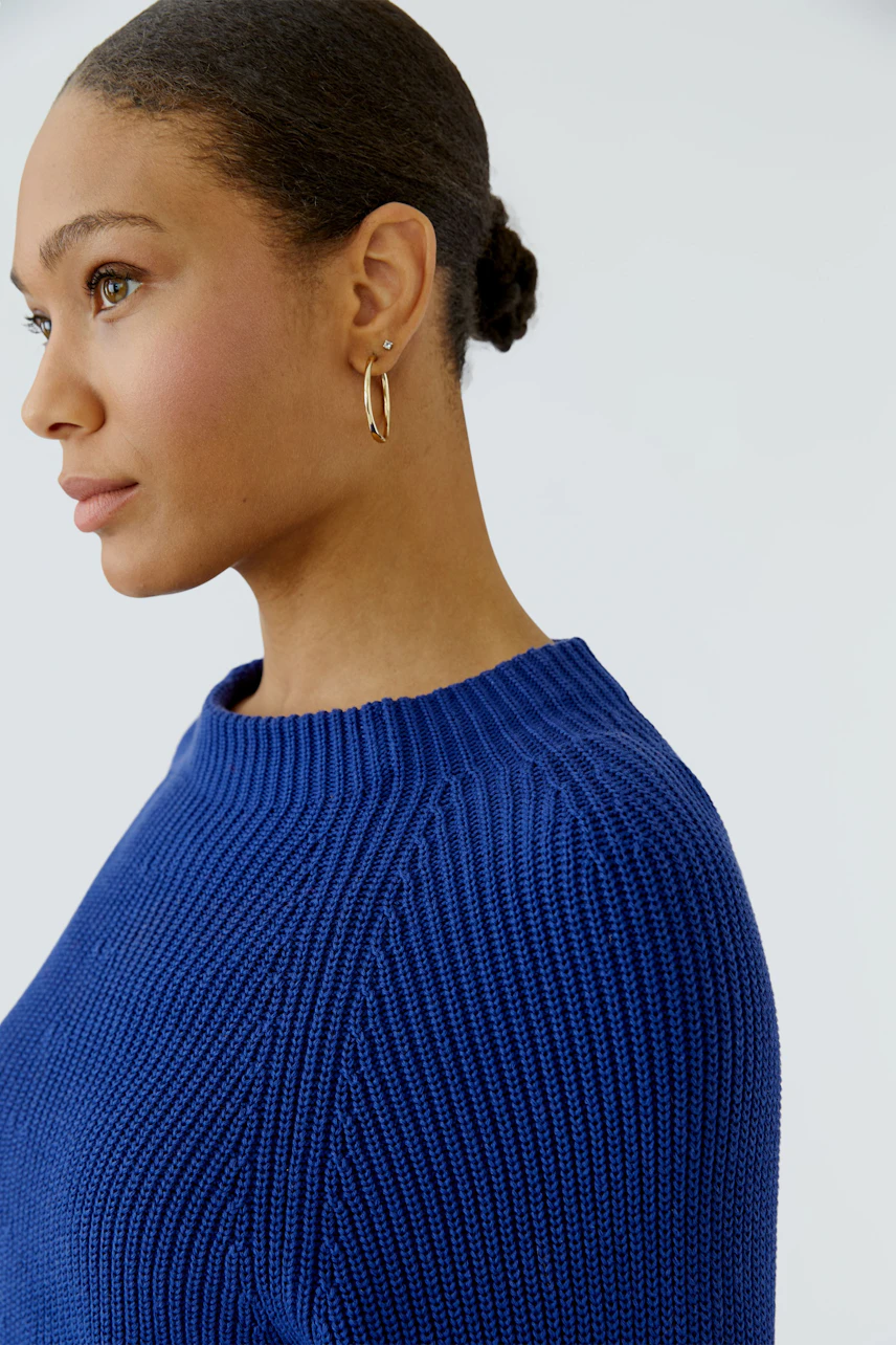 Woman in a blue pullover with a simple design, showcasing a casual and modern look.