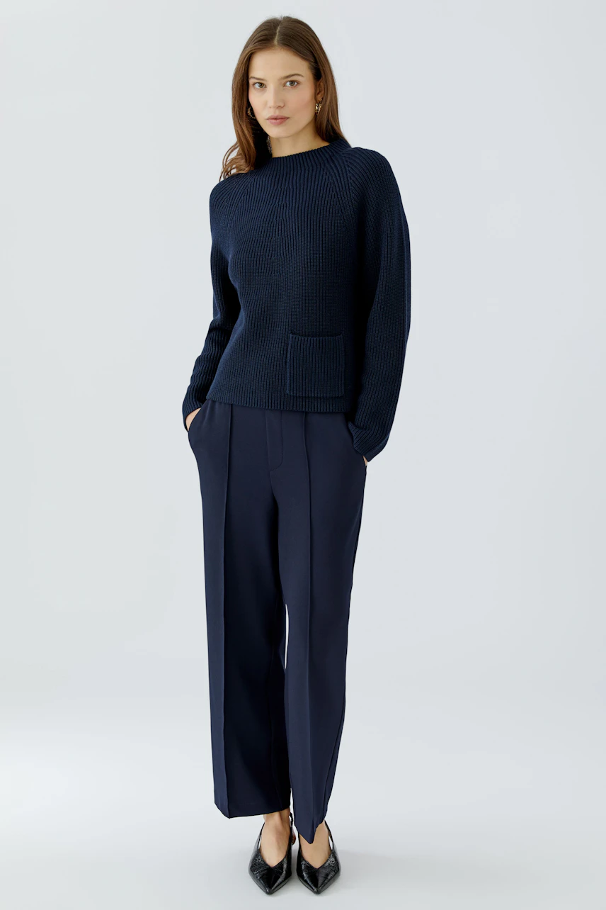 Casual women's pullover: Woman in navy knit pullover with pocket, paired with matching trousers.
