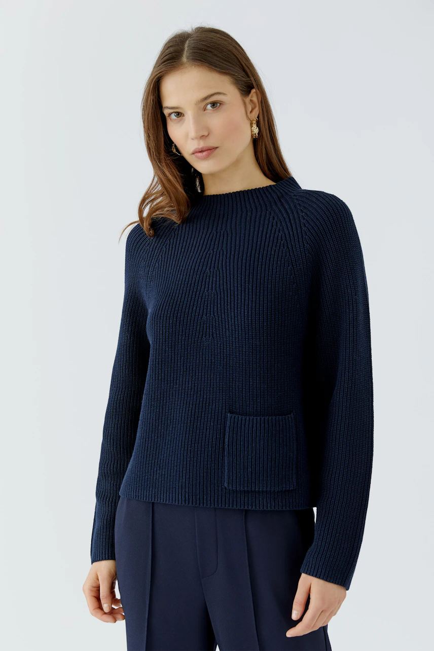Casual women's pullover: Woman in navy knit pullover with pocket, paired with matching pants, looks relaxed.