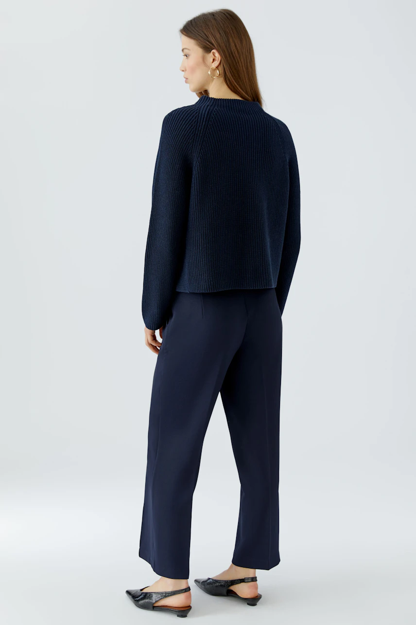 Woman in navy pullover and matching pants, standing sideways. Casual and modern look.