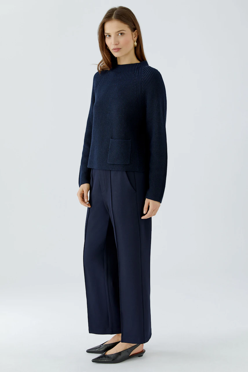 Casual women's pullover: Woman in a navy pullover with wide-leg pants, standing confidently.