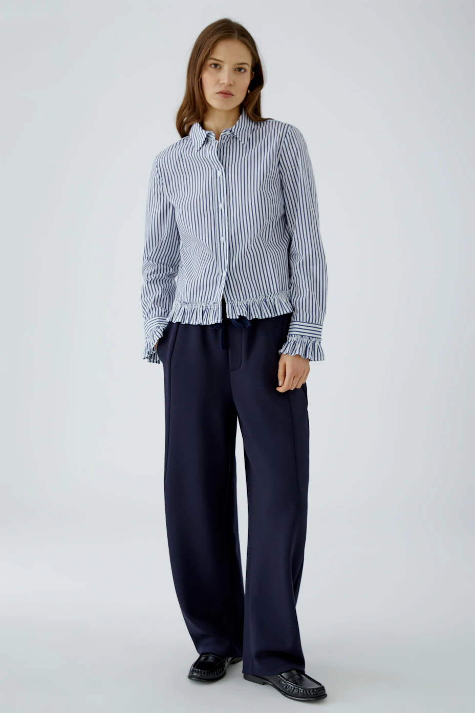 Striped women's blouse with ruffled hem and cuffs, perfect for a casual look.