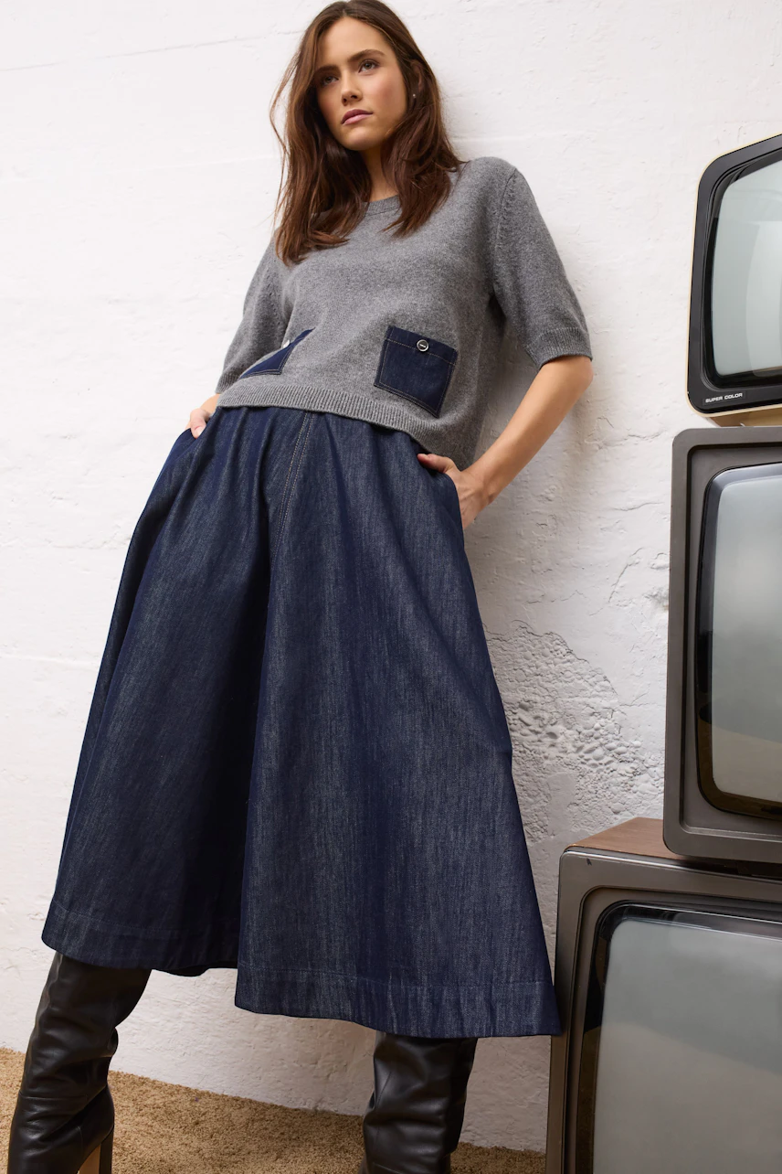 A-line skirt: Woman in a cozy sweater and faux fur jacket, wearing a flowing denim A-line skirt.