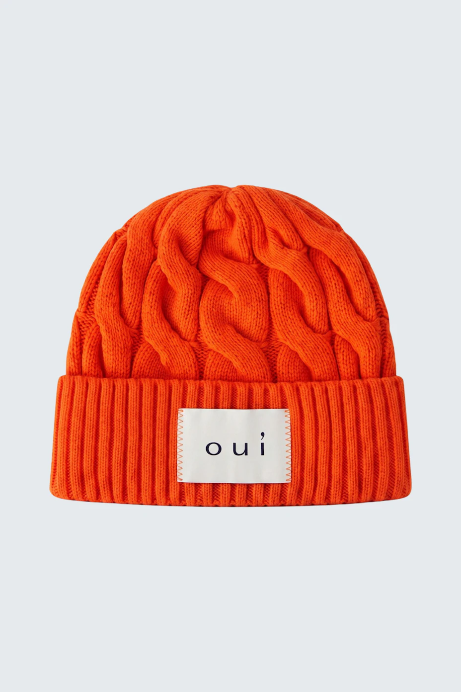 Strickmütze in leuchtendem Orange mit Zopfmuster und Oui-Logo, ideal für kalte Tage.
