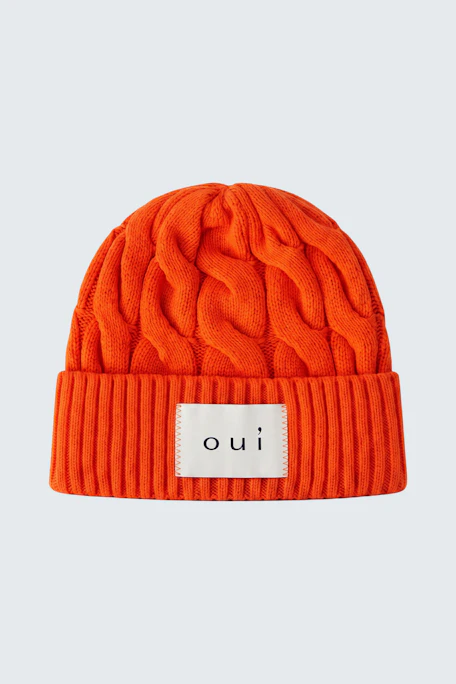 Strickmütze in leuchtendem Orange mit Zopfmuster und Oui-Logo, ideal für kalte Tage.