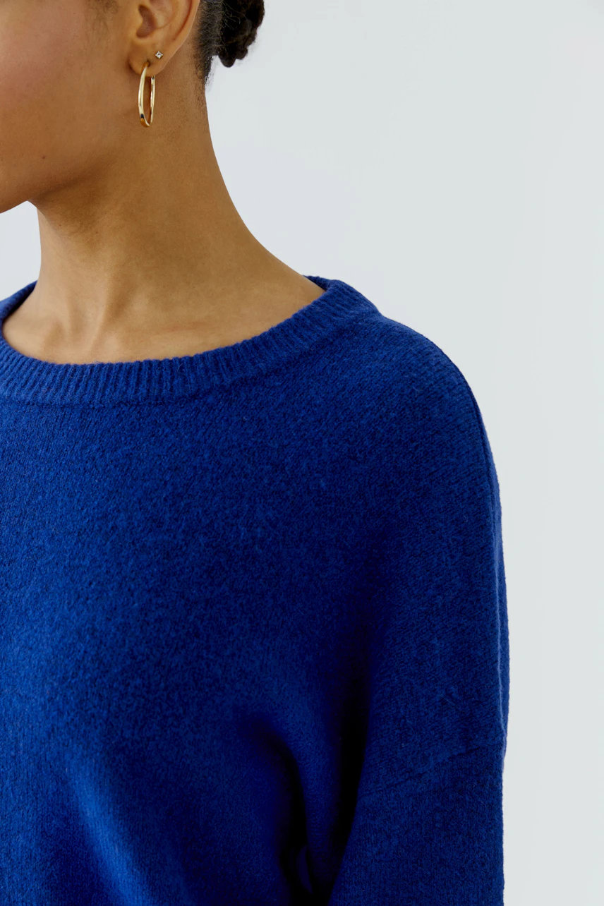 Frau im blauen Pullover: Schlichter, bequemer Strickpullover mit Rundhalsausschnitt, ideal für den Alltag.