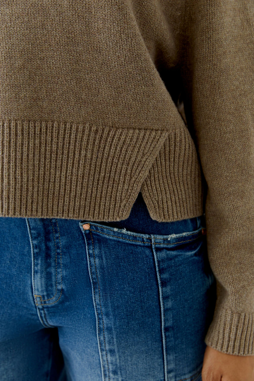 Lässiger Damen-Pullover: Frau in braunem Pullover kombiniert mit blauer Jeans, seitlich fotografiert.