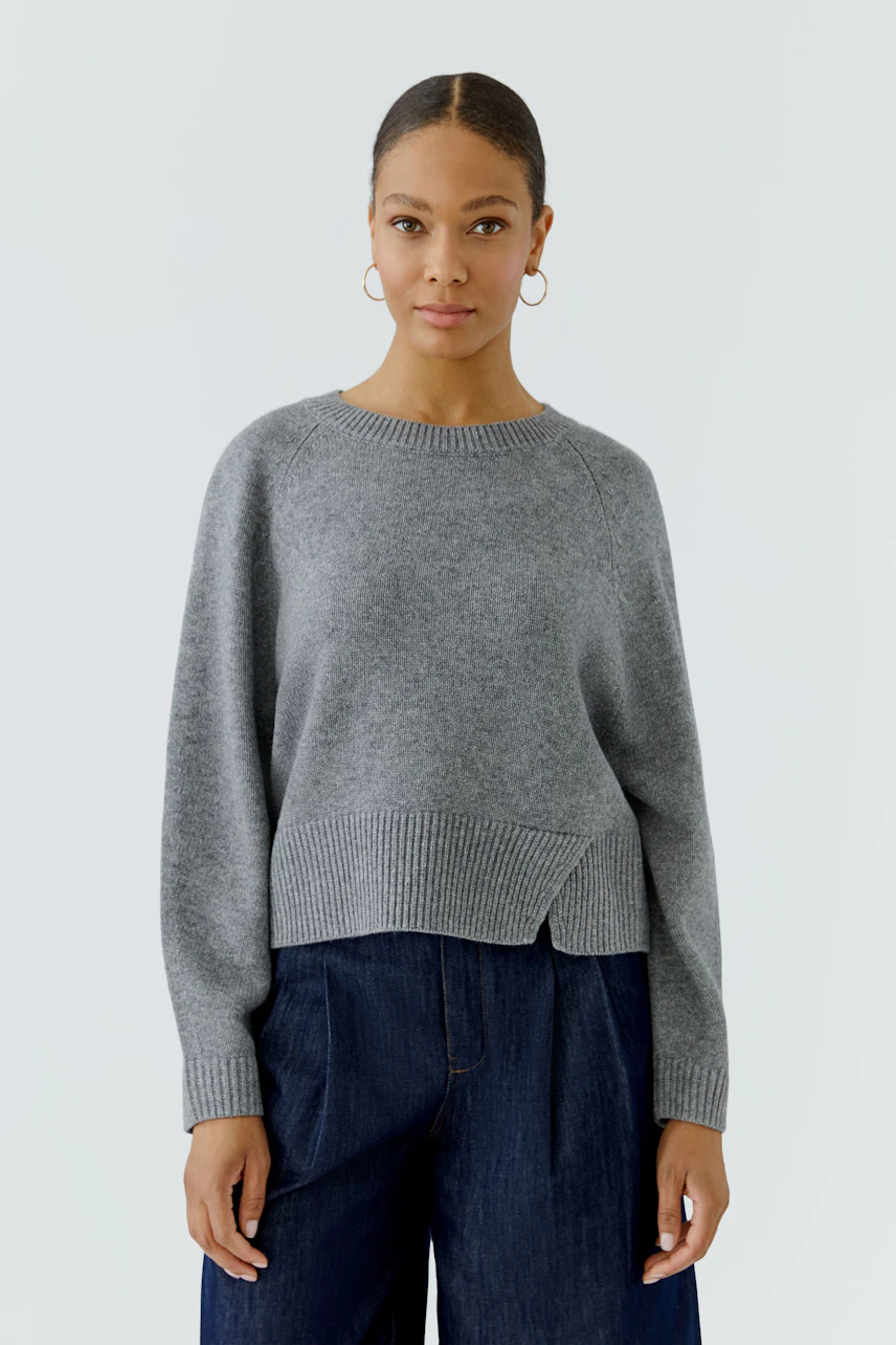 Casual women's pullover: Woman in a grey pullover with relaxed fit and dark wide-leg jeans.