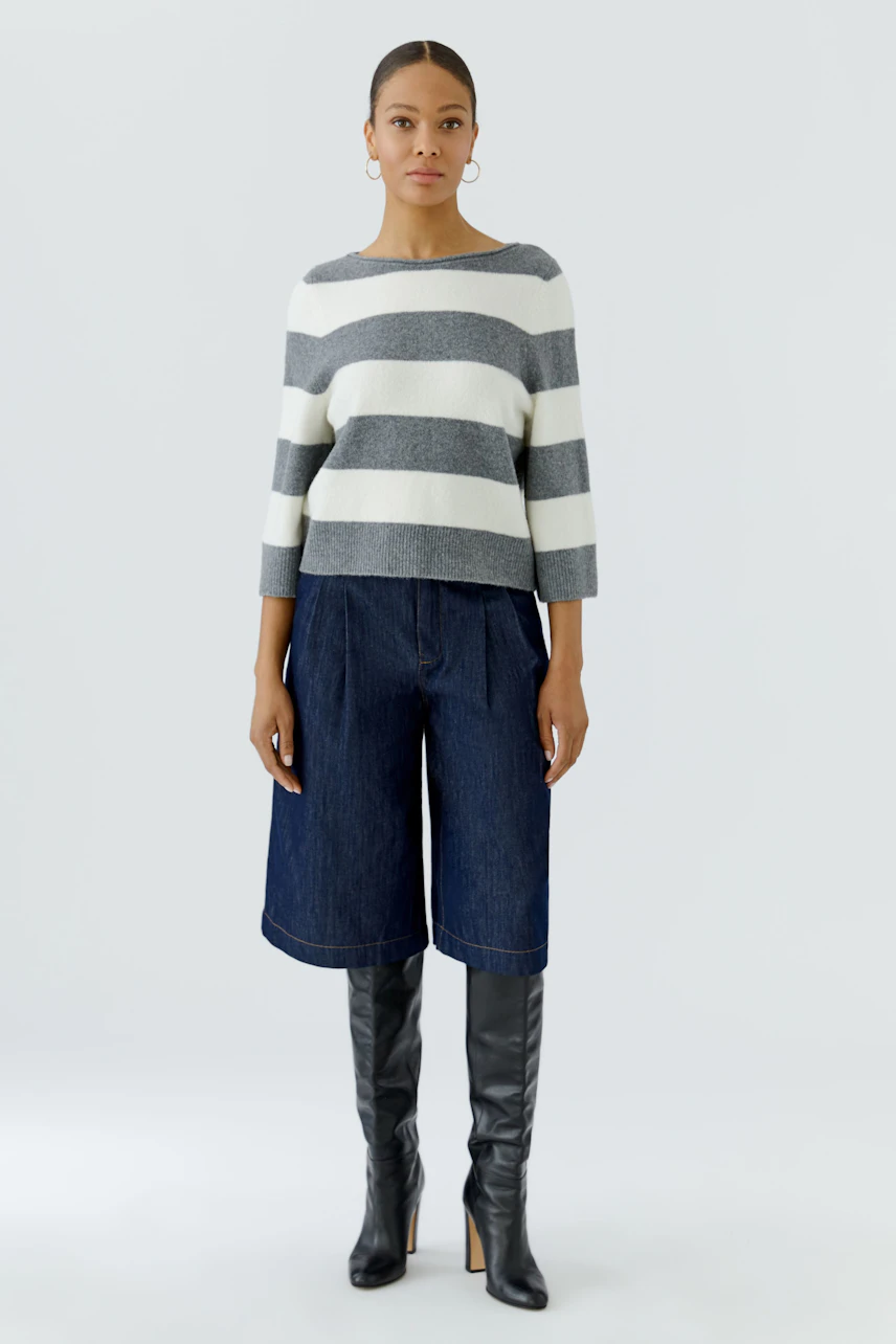 Striped pullover: Woman in a casual striped pullover with wide-leg jeans and knee-high boots.