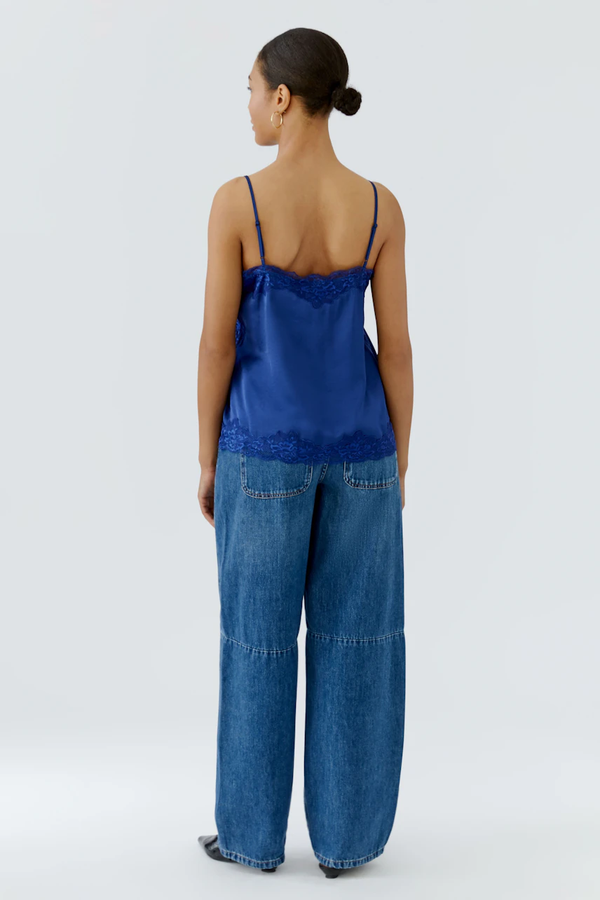 Woman in blue lace-trimmed top and wide-leg jeans, viewed from the back.