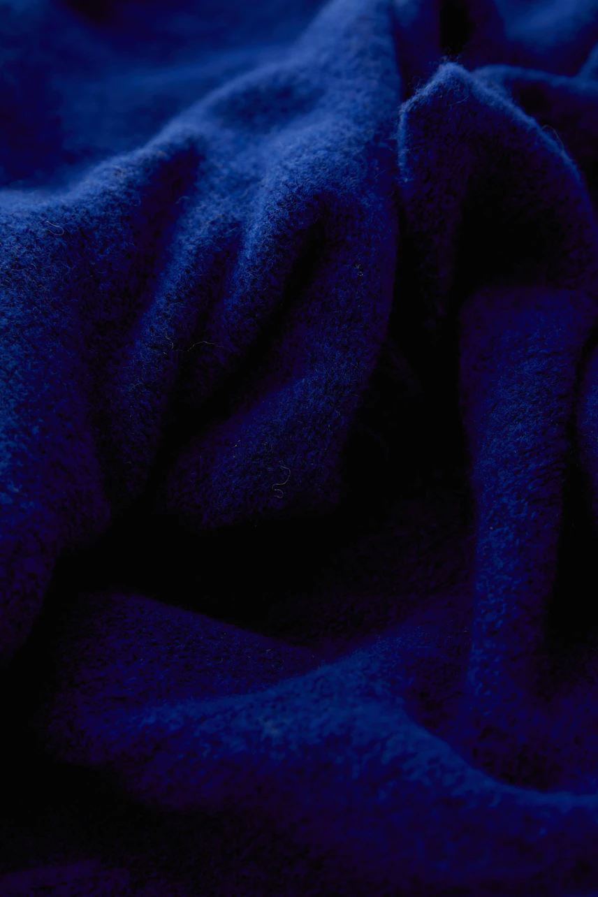 Weicher blauer Schal: Detailaufnahme des Stoffes, zeigt die flauschige Textur und satte Farbe.