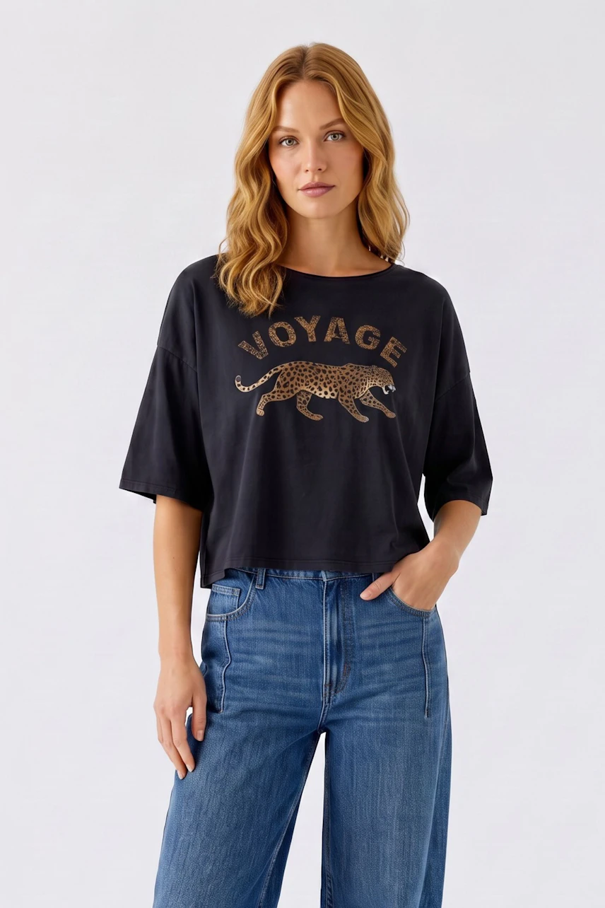 Casual women's T-shirt: Woman in black T-shirt with leopard print and 'Voyage' text, paired with blue jeans.