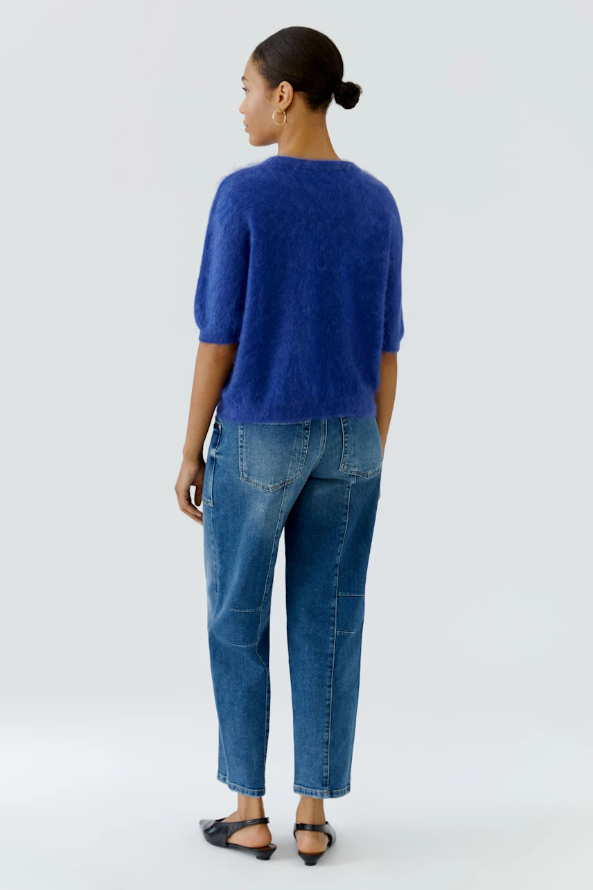 Frau im blauen Pullover und Jeans, von hinten. Lässiger Look für den Alltag.
