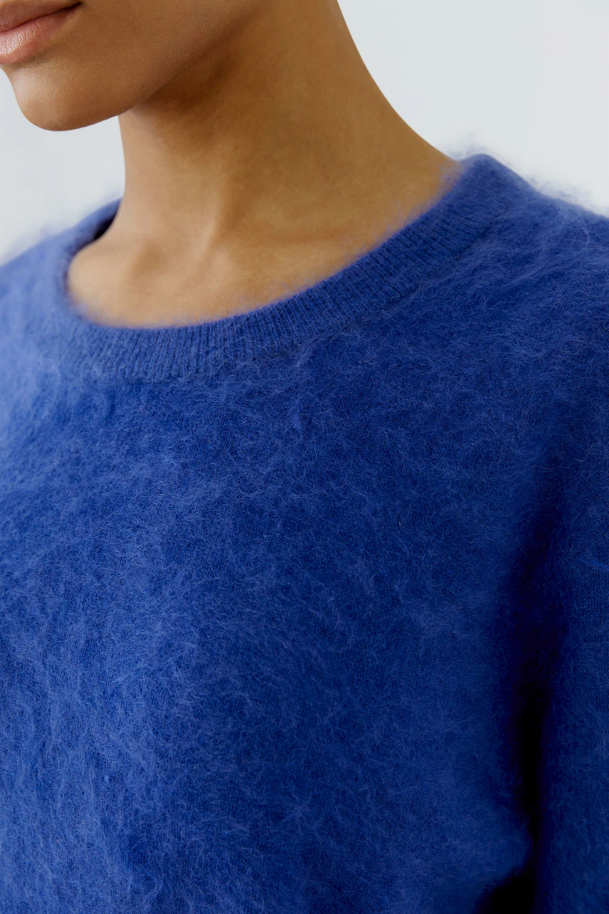 Flauschiger Damen-Pullover: Frau trägt blauen Pullover mit weichem, flauschigem Material.
