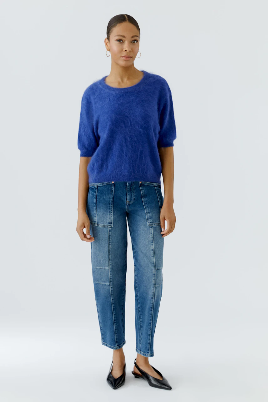 Frau im blauen Pullover und Jeans, lässiger Look, schlicht und modern.