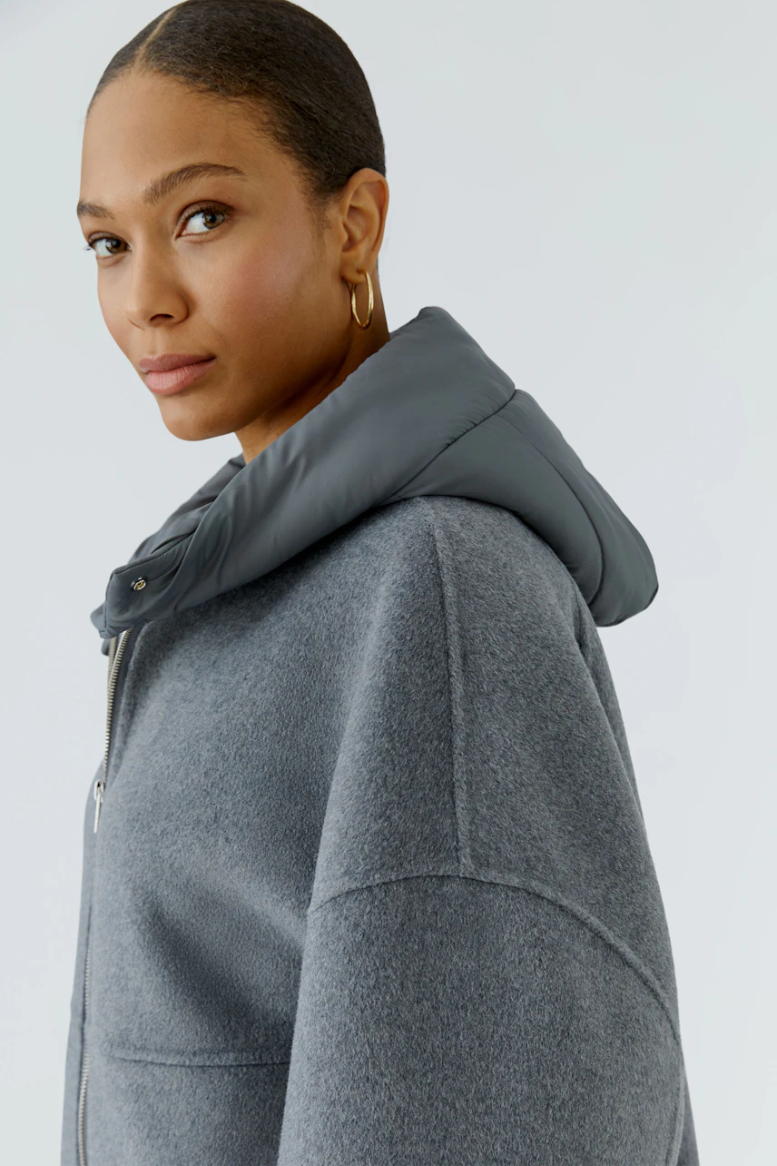 Casual women's jacket: Woman in a grey hooded jacket with a relaxed fit, looking confidently.