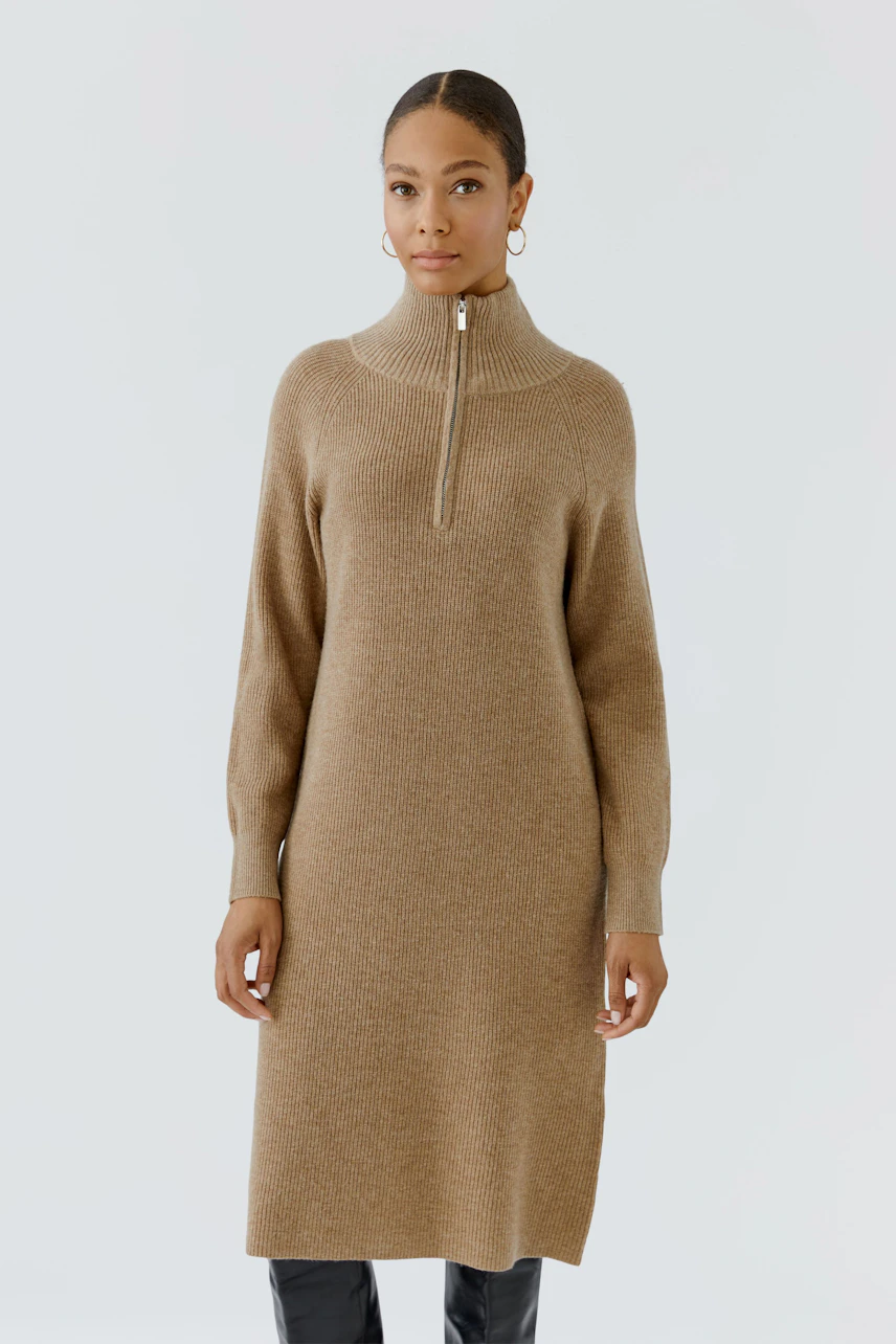 Casual knit dress: Woman in a brown knit dress with a high collar and zipper, paired with black boots.
