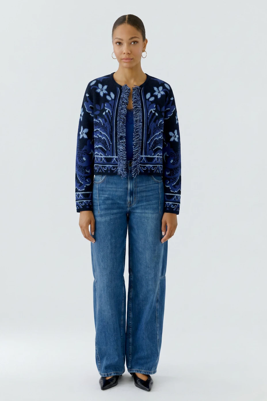 Strickjacke in Blau mit floralem Muster und Fransen, ohne Model abgebildet.