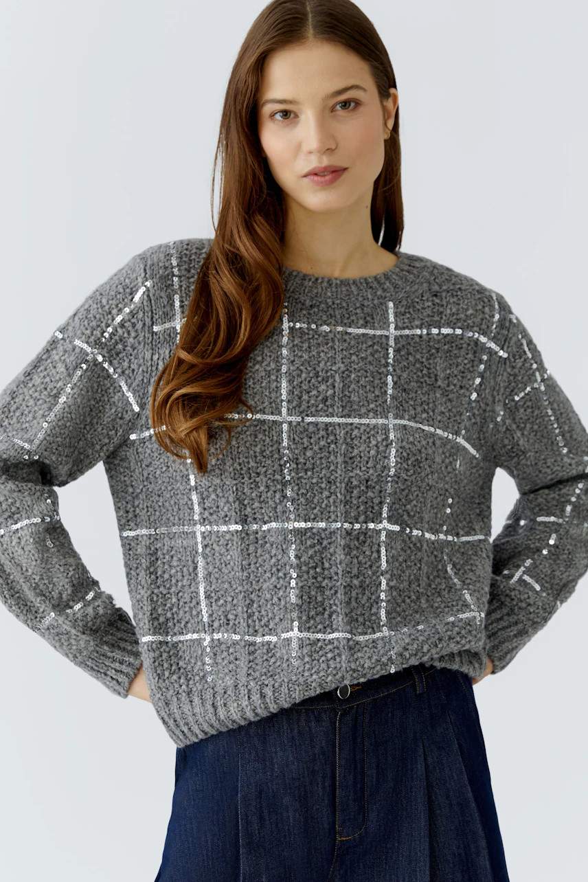 Casual women's pullover: Woman in a grey checkered pullover with relaxed fit and long sleeves.