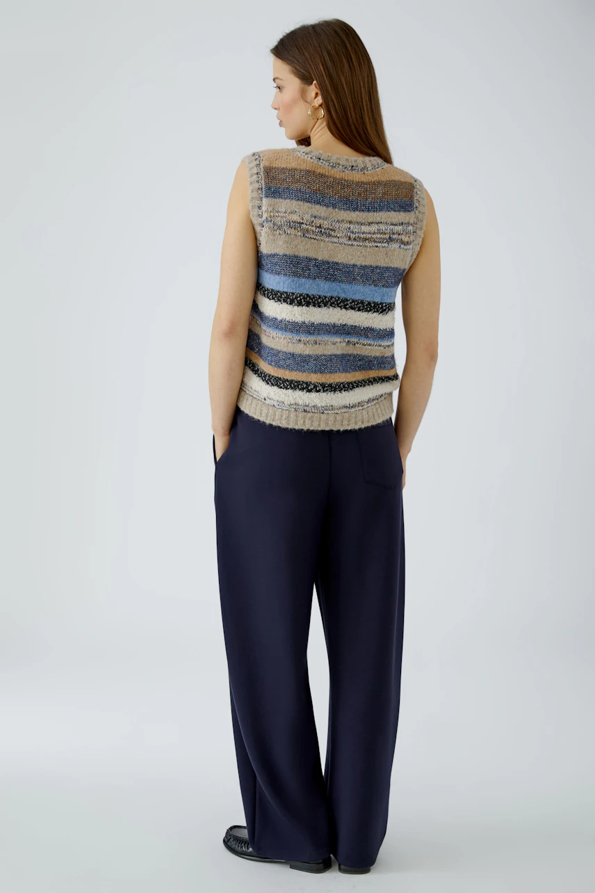 Striped pullover vest: Woman in a sleeveless knit vest with blue and beige stripes, paired with navy pants.