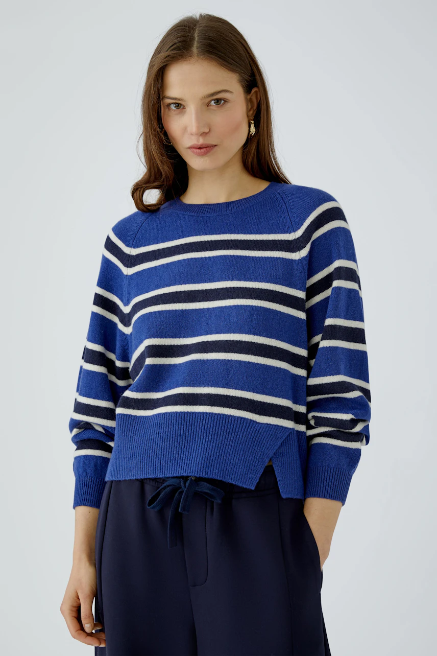Casual women's pullover: Woman in a blue and white striped pullover with relaxed navy pants.