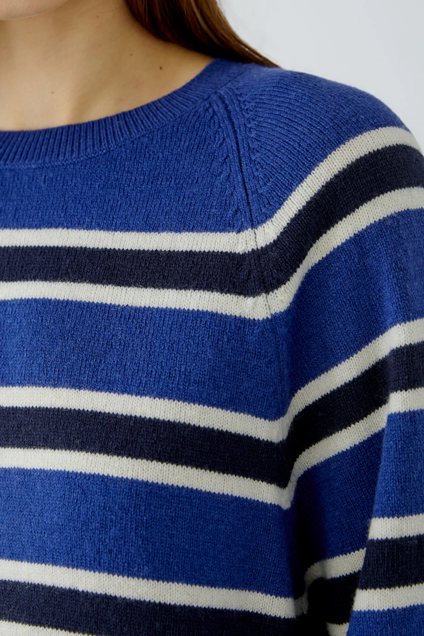 Striped pullover: Woman in a blue and white striped pullover, close-up of the knit texture.