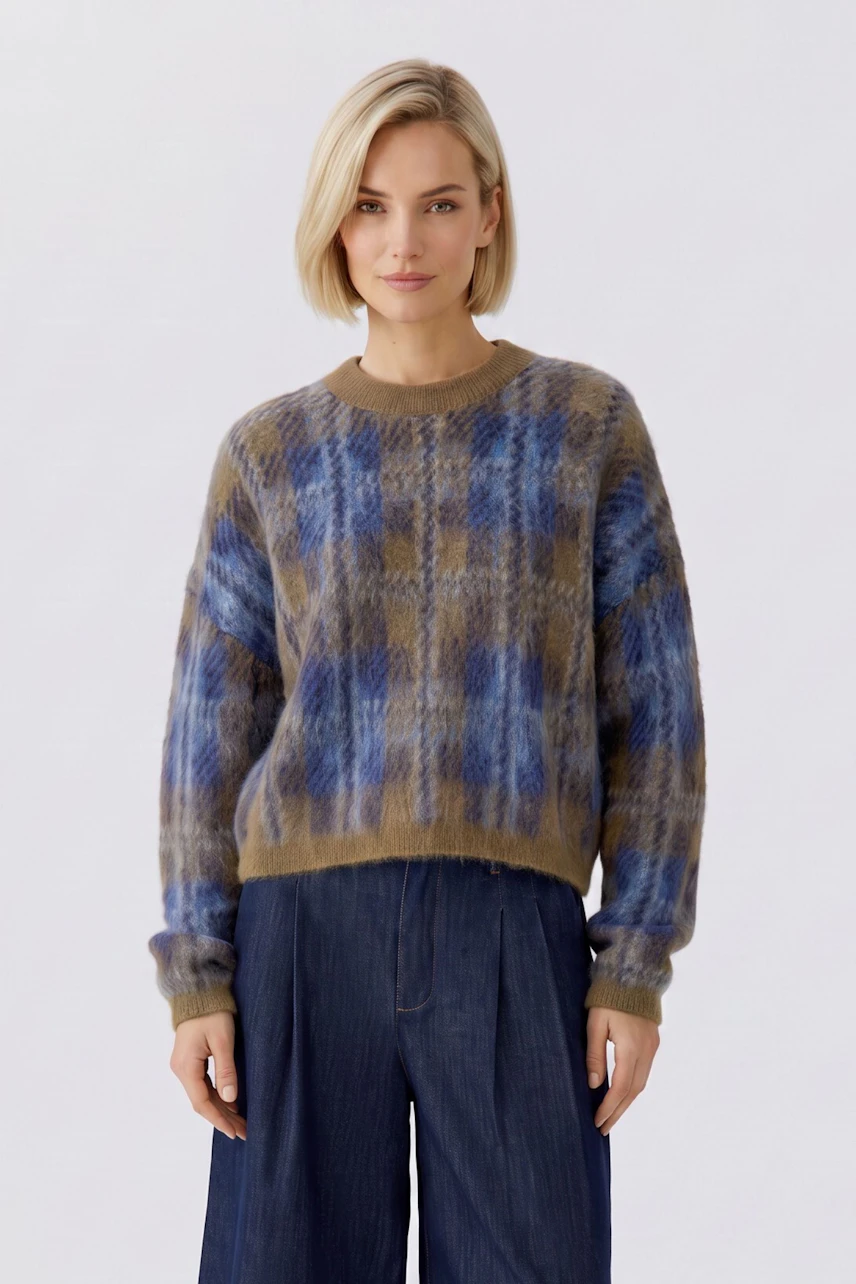 Casual women's pullover: Woman in a blue and brown plaid pullover with relaxed fit, paired with denim pants.