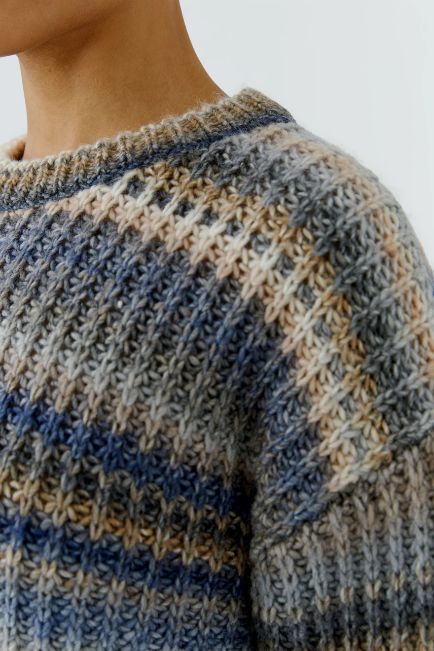 Cozy women's pullover: Close-up of textured knit in blue and beige tones, worn by a woman.